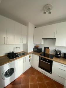 a kitchen with white cabinets and a sink and a dishwasher at Apartament Kasia in Wałbrzych