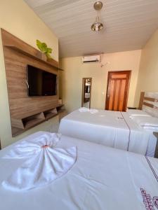 a hotel room with two beds and a flat screen tv at Hotel Campos in Itaituba