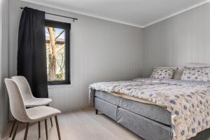 Egersund Overnatting في إيجرشوند: غرفة نوم بسرير وكرسي ونافذة