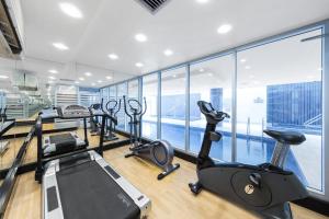 een fitnessruimte met loopbanden en crosstrainers in een kamer met ramen bij Oaks Glenelg Liberty Suites in Adelaide