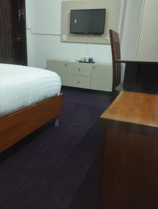 1 dormitorio con 1 cama y TV en la pared en Trail Residency en Islamabad