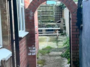 an archway in a brick building with a bench in a yard at Stunning 3 BED 2BATH house w/parking in Reading