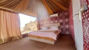 a bedroom with a bed and a large window at Al Raha Luxury Camp in Wadi Rum
