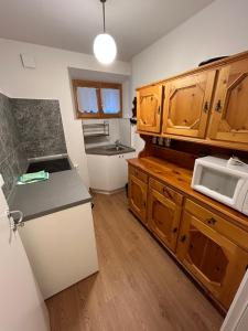 cocina con armarios de madera y microondas blanco en Residenza Sertorelli, en Bormio
