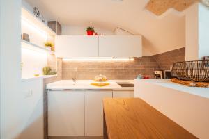 a kitchen with white cabinets and a wooden table at Bianca Relax & SPA - Housea in Polignano a Mare