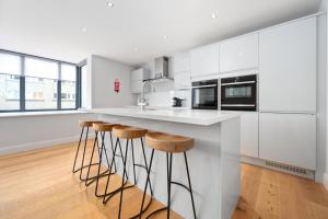 a kitchen with white cabinets and bar stools at White Hart Hotel & Apartments in Harrogate