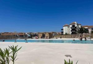 a large swimming pool with people in the water at Appartement T2 dans jolie résidence avec piscine in Le Barcarès