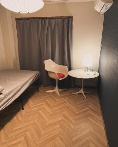 a room with a bed and a table and a chair at Hostel UND BASE in Saiki