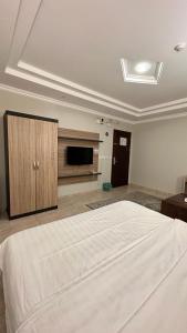 a bedroom with a large bed and a flat screen tv at شموع المروج للوحدات الفندقية in Tabuk