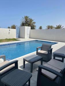 una piscina con sillas y una mesa junto a ella en Superbe villa avec piscine sans aucun vis à vis, en Djerba