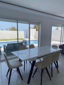 a dining room with a table and chairs and a pool at Superbe villa avec piscine sans aucun vis à vis in Djerba