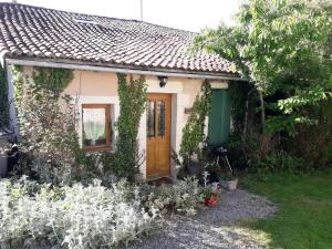 una pequeña casa con una puerta marrón y algunas flores en Tranquille Vienne Gites, en Chirac
