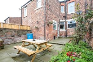 a wooden picnic table in front of a brick building at 5 bedroom house, free parking, near football, sleeps 8 in Liverpool