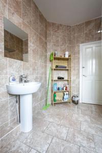 a bathroom with a white sink and a tiled floor at 5 bedroom house, free parking, near football, sleeps 8 in Liverpool +30 photos
