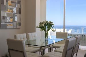 a dining room with a glass table and white chairs at Azure Sky Villa - Panoramic ocean view, luxury, San Eugenio in Adeje