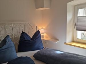 ein Schlafzimmer mit einem Bett mit blauen Kissen und einem Fenster in der Unterkunft Kapellenblick in Bad Häring