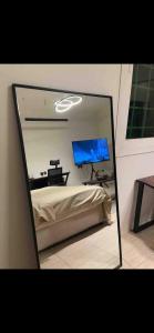espejo que refleja un dormitorio con cama y TV en استديو بتصميم عصري ومريح في موقع مميز en Riad