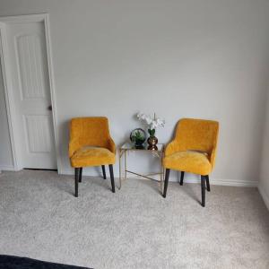 duas cadeiras cor-de-laranja e uma mesa num quarto em Maison EMN em Fort Worth