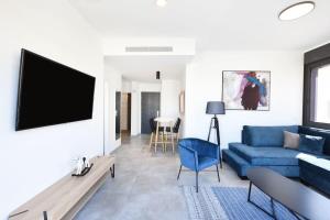 a living room with a blue couch and a tv at Marine Pearl by HolyGuest in Tel Aviv