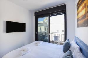 a bedroom with a white bed with a large window at Marine Pearl by HolyGuest in Tel Aviv