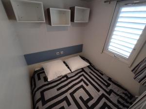 a small bedroom with a bed and a window at Mobil home à louer dans camping des cigales le muy 5 étoiles in Le Muy +6 photos