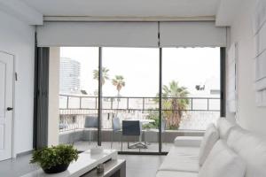 een woonkamer met een witte bank en een groot raam bij Pearl & Caviar by Holyguest in Tel Aviv