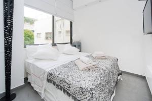 een witte slaapkamer met een bed met handdoeken erop bij Pearl & Caviar by Holyguest in Tel Aviv