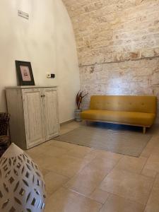 un divano giallo in una stanza con muro di mattoni di Masseria I Raffi b&b a Monopoli