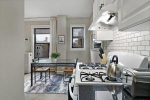 a kitchen with a stove top oven next to a table at Elegant 1-Bedroom Apartment in Hyde Park - Windermere 310 in Chicago