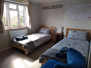 a bedroom with two beds and a chair and a window at Lovely 3 bed house, luxury hot tub, EV charger and free parking for 2 cars in Thorpe Saint Andrew