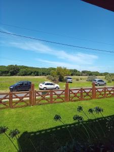 una valla de madera con coches aparcados en un campo en Habitación frente al mar en Mar del Plata