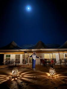 a man standing in front of a building at night at Desert Waves Excursion in Mhamid