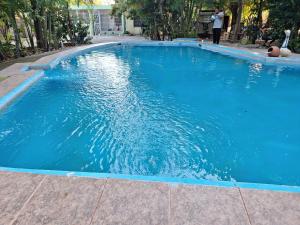 a large blue swimming pool with a person standing in it at Habitación con piscina,Netflix Hotel Villa Marchena in Azua de Compostela