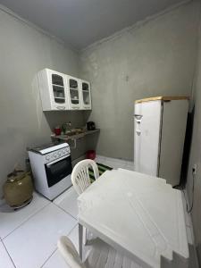 cocina con nevera, mesa y silla en Flat Nogueira, en Palmas