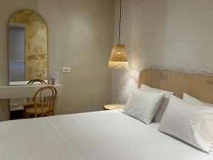 a bedroom with a bed with white sheets and a mirror at Dimitri Hotel in Himare