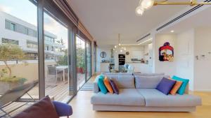 een woonkamer met een bank met kussens bij Colorful Shenkin 3-BR by HolyGuest in Tel Aviv