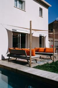 - 2 bancs avec des oreillers orange installés à côté de la piscine dans l'établissement Bright Contemporary House - Private Pool, à LʼIsle-sur-la-Sorgue
