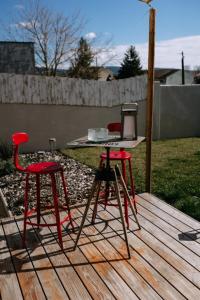 2 chaises rouges et une table sur une terrasse en bois dans l'établissement Bright Contemporary House - Private Pool, à LʼIsle-sur-la-Sorgue