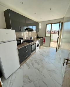 uma cozinha com um frigorífico branco e uma máquina de lavar louça em Appartement haut standing proche Océan em Salé