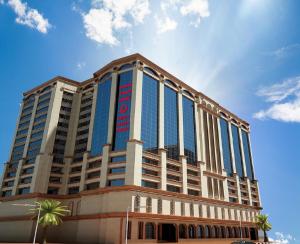 un grande edificio con finestre blu e una palma di Amjad Al Deafah Hotel a La Mecca