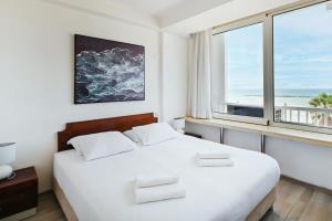 een slaapkamer met een wit bed en een groot raam bij Beach Front 2BR in Sea Hotel by HolyGuest in Tel Aviv