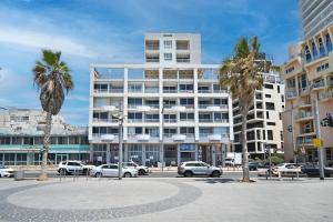 een groot gebouw met palmbomen ervoor bij Beach Front 2BR in Sea Hotel by HolyGuest in Tel Aviv