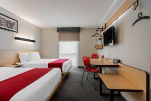 a hotel room with two beds and a desk at City Express by Marriott Queretaro Jurica in Quer&eacute;taro