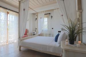 a white bedroom with a white bed and windows at Tas Bahce Hotel Cunda in Ayvalık