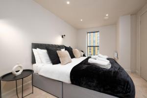 een slaapkamer met een groot bed met zwart-witte kussens bij Luxury Serviced Penthouse - City Centre - En Suite Bedrooms - Free Netflix in Leeds