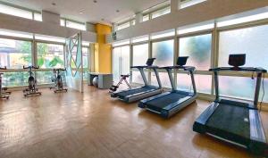 een fitnessruimte met diverse loopbanden in een kamer met ramen bij K&K The Modern Crib in Biñan