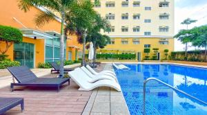 a swimming pool with chairs and a building at K&K The Modern Crib at Holland Park Condo Southwoods City in Biñan