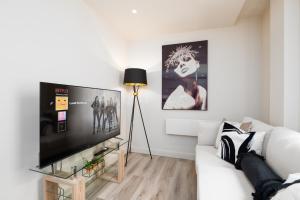 a living room with a white couch and a flat screen tv at Luxury Serviced Penthouse - City Centre - En Suite Bedrooms - Free Netflix in Leeds