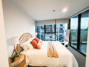 a bedroom with a white bed with pillows on it at Heart of City - Pool - Parking - Self check-in in Canberra +14 photos