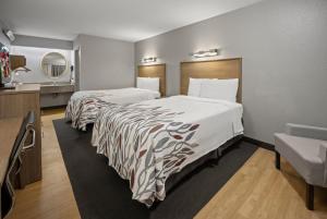 ein Hotelzimmer mit 2 Betten und einem Spiegel in der Unterkunft Red Roof Inn Greensboro Airport in Greensboro